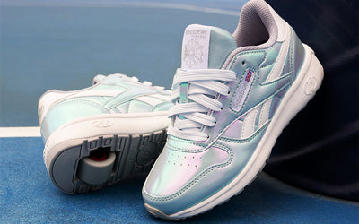 Pair of light blue and white Reebok x Heelys shoes on a blue surface
