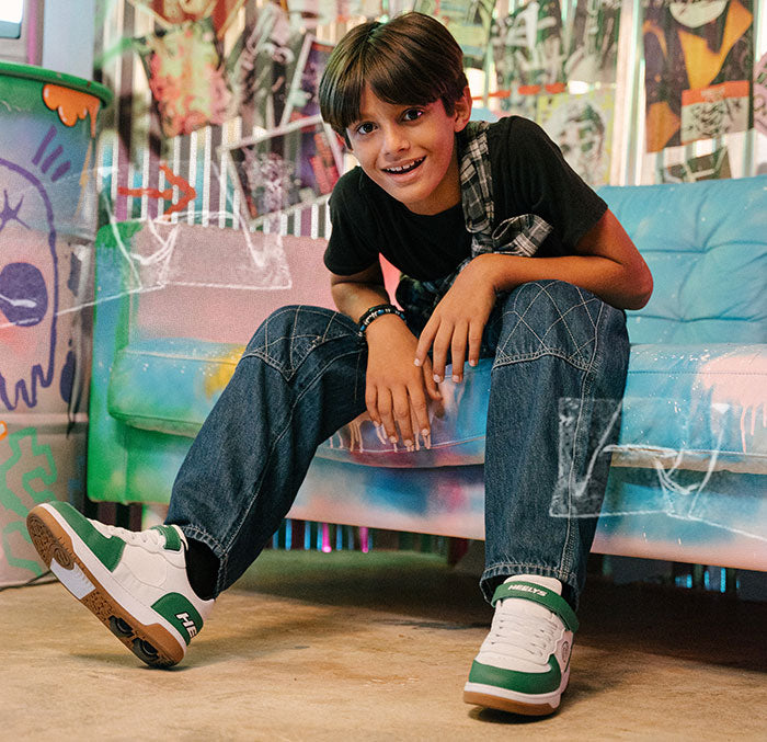 Boys Heelys roller shoes. Child sitting on a colorful sofa with a vibrant background