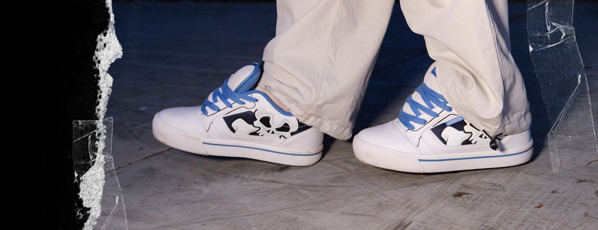 How to Heely. White Heelys roller shoes with blue accents worn by a person gliding on a concrete floor.